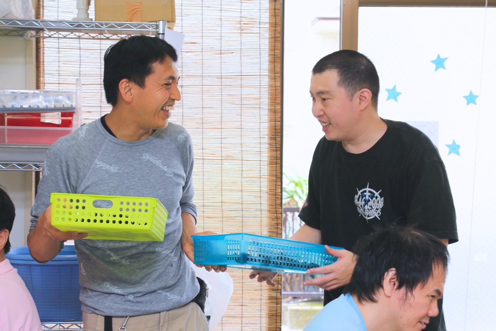 作業中笑顔で顔を合わせるスタッフと利用者さんの様子